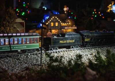 Model train passing a lit-up miniature village
