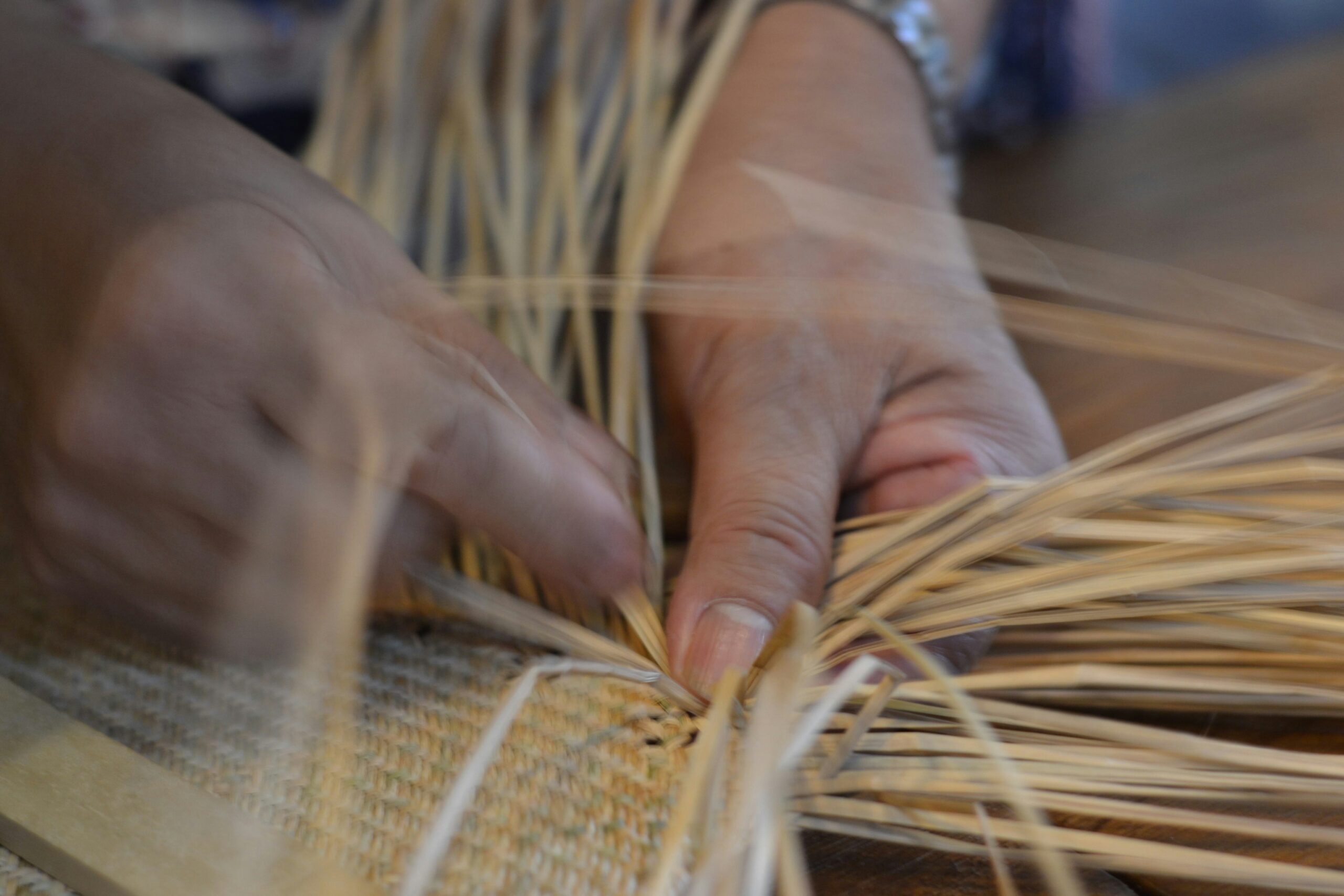 close up of hands weaving a basket